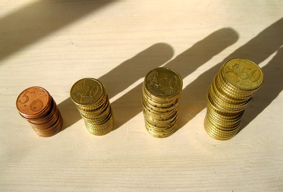 Four towers of euro cent coins of increasing height, casting long shadows.
