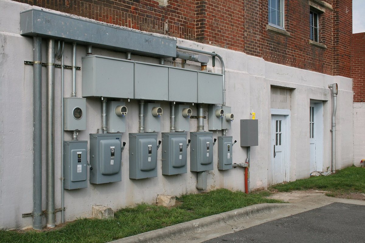 A row of electricity meters and disconnect switches mounted on the outside wall of a building in Durham, North Carolina.