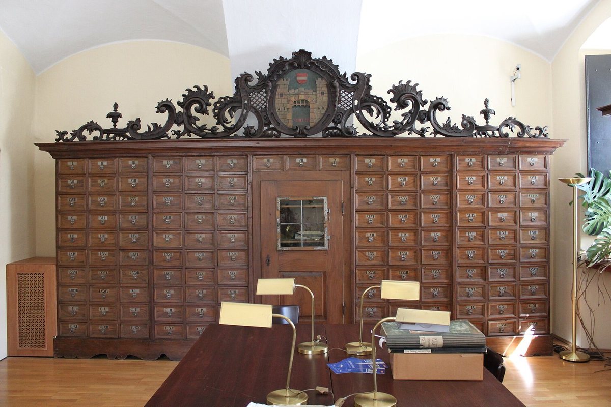 A tall wooden archive cabinet of small drawers in the reading room of an archive.